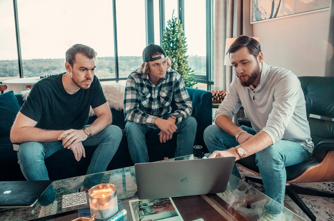 Diverse group of colleagues gathered around a laptop discussing work